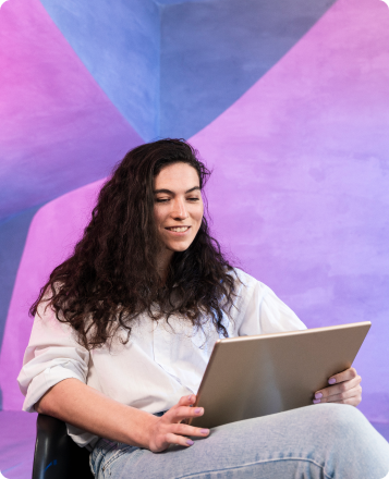 Joven sentada frente a un notebook con fondo colorido
