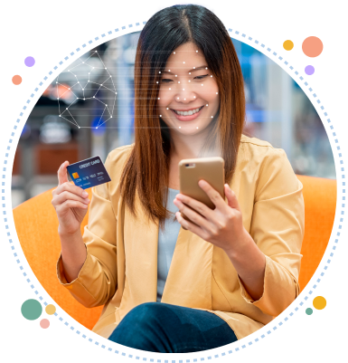 Mujer sonriendo mientras verifica su rostro con el celular y sostiene una tarjeta de crédito